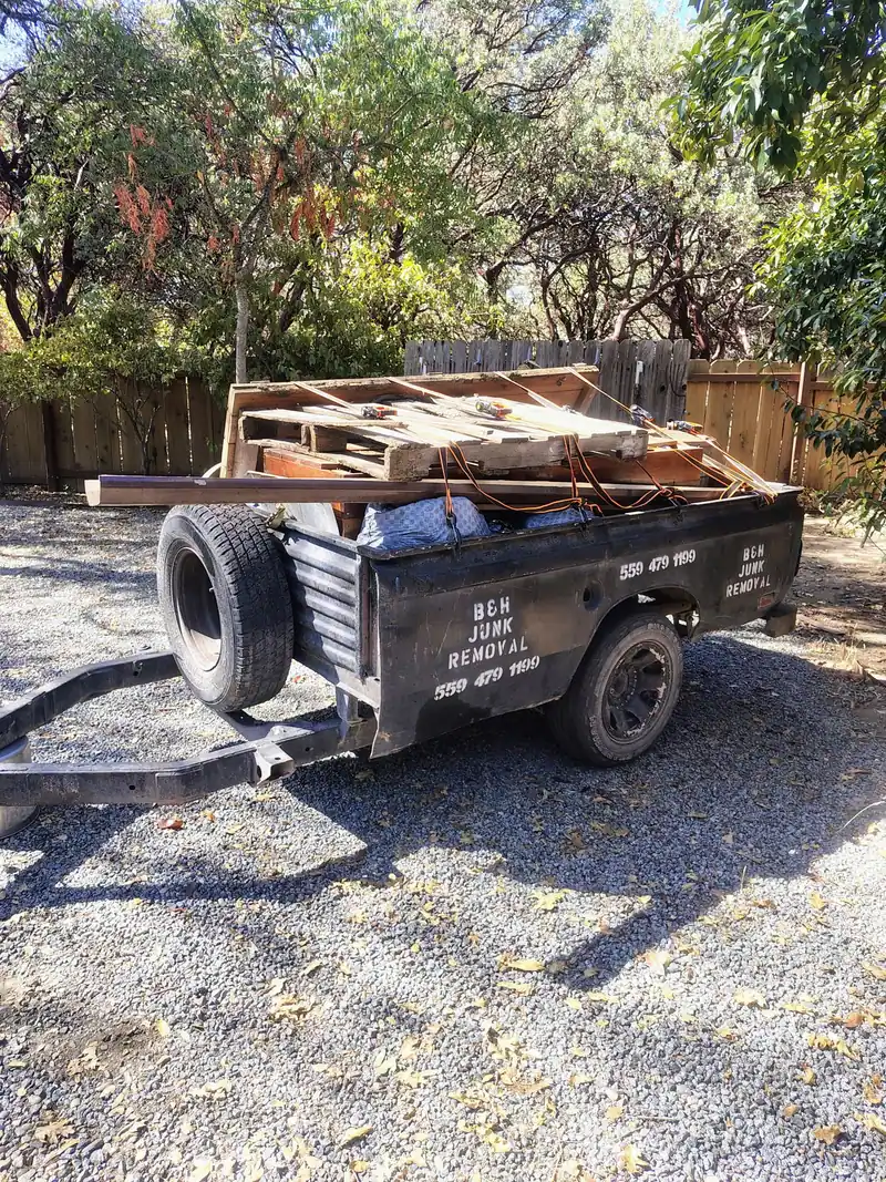 The B&H Junk Removal trailer loaded with pallets and cut lumber; strapped down