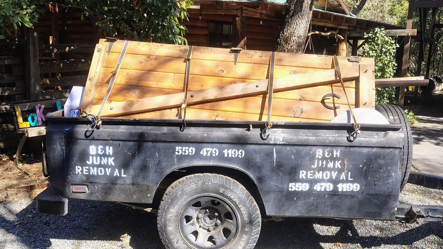 The B&H Junk Removal trailer loaded with fresh cut timber and strapped down
