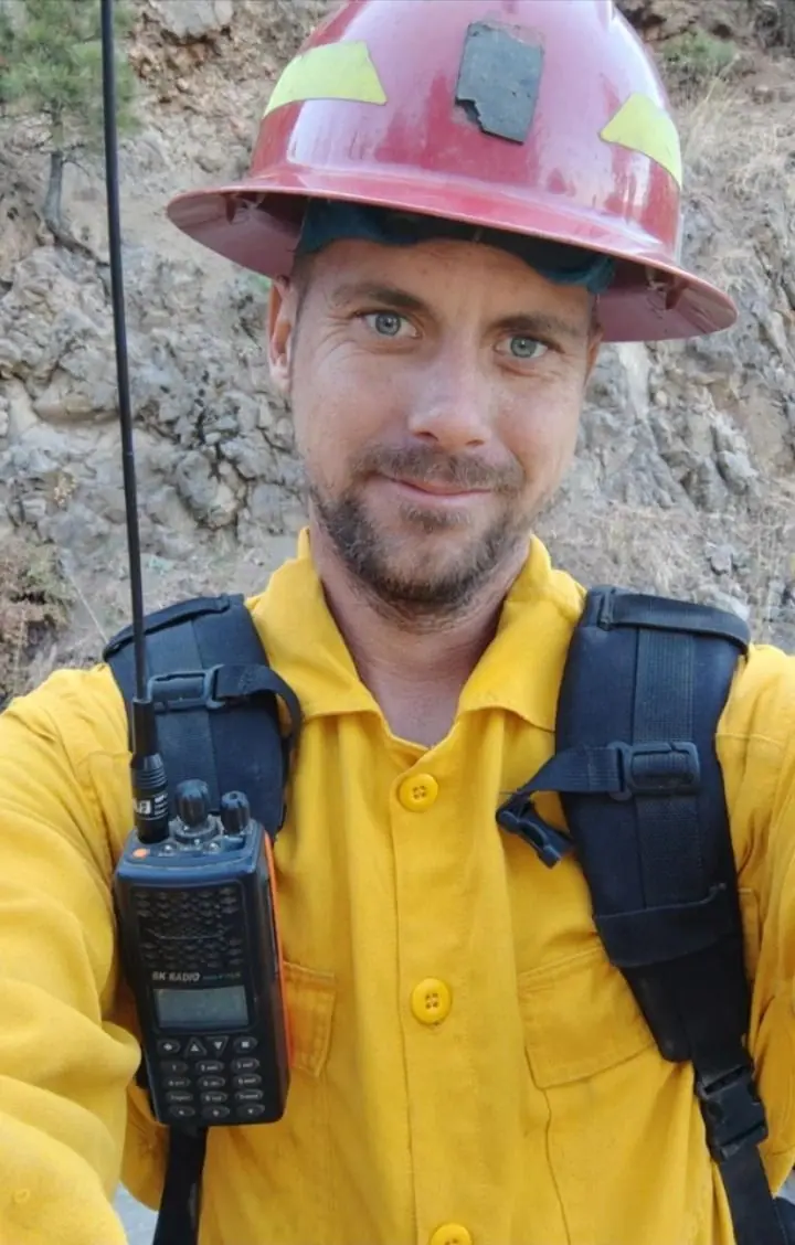 Brandon Woodhouse in his wildland fire helmet with a radio on his pack strap