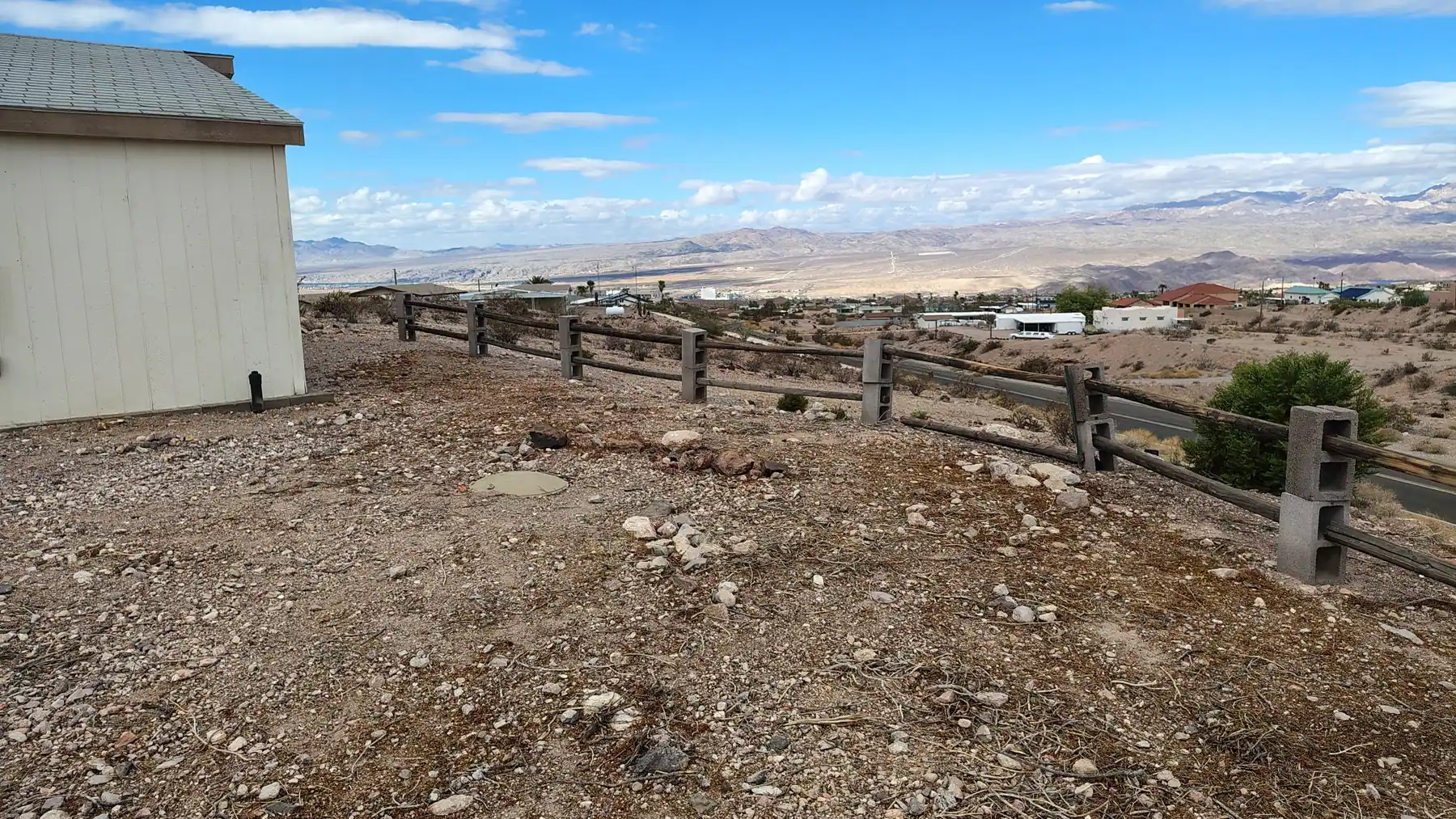 A cleared gravel lot behind a rail fence with the valley and mountains beyond