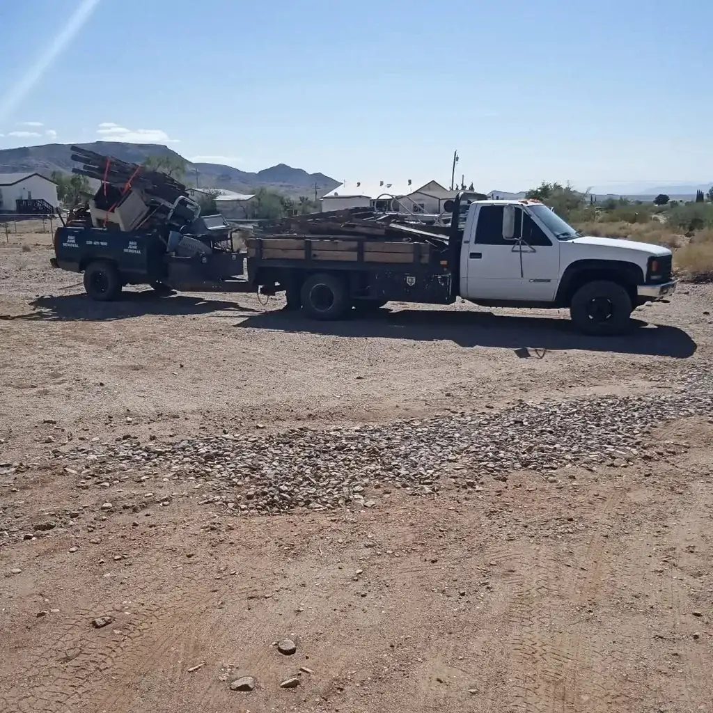 A flatbed truck and a truck bed trailer both loaded with old lumber