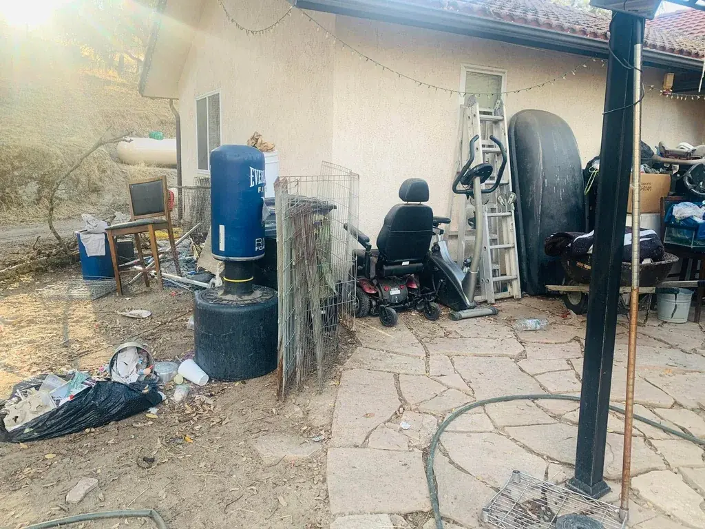 A side yard filled with wire cages, a punching bag and cut branches