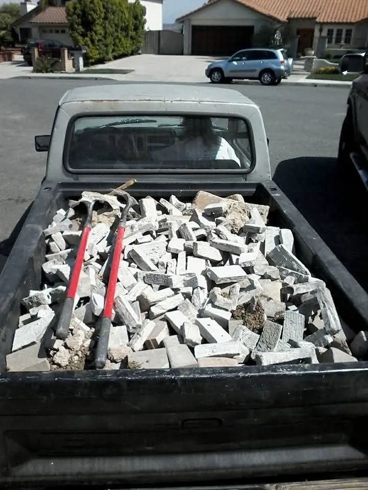 A truck bed loaded with broken concrete, brick and two sledgehammers