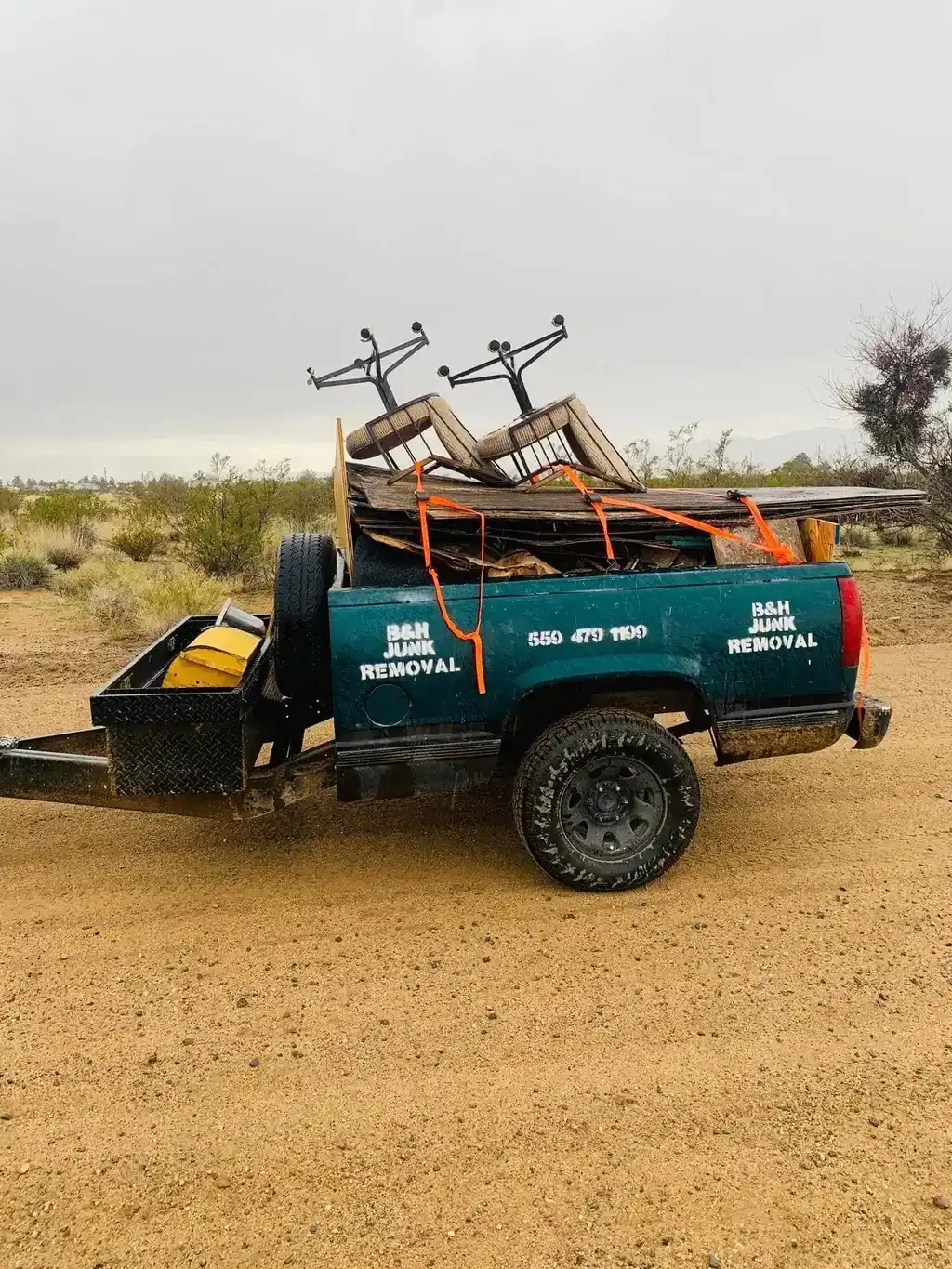 Old lumber and folding chairs strapped down on a truck bed trailer