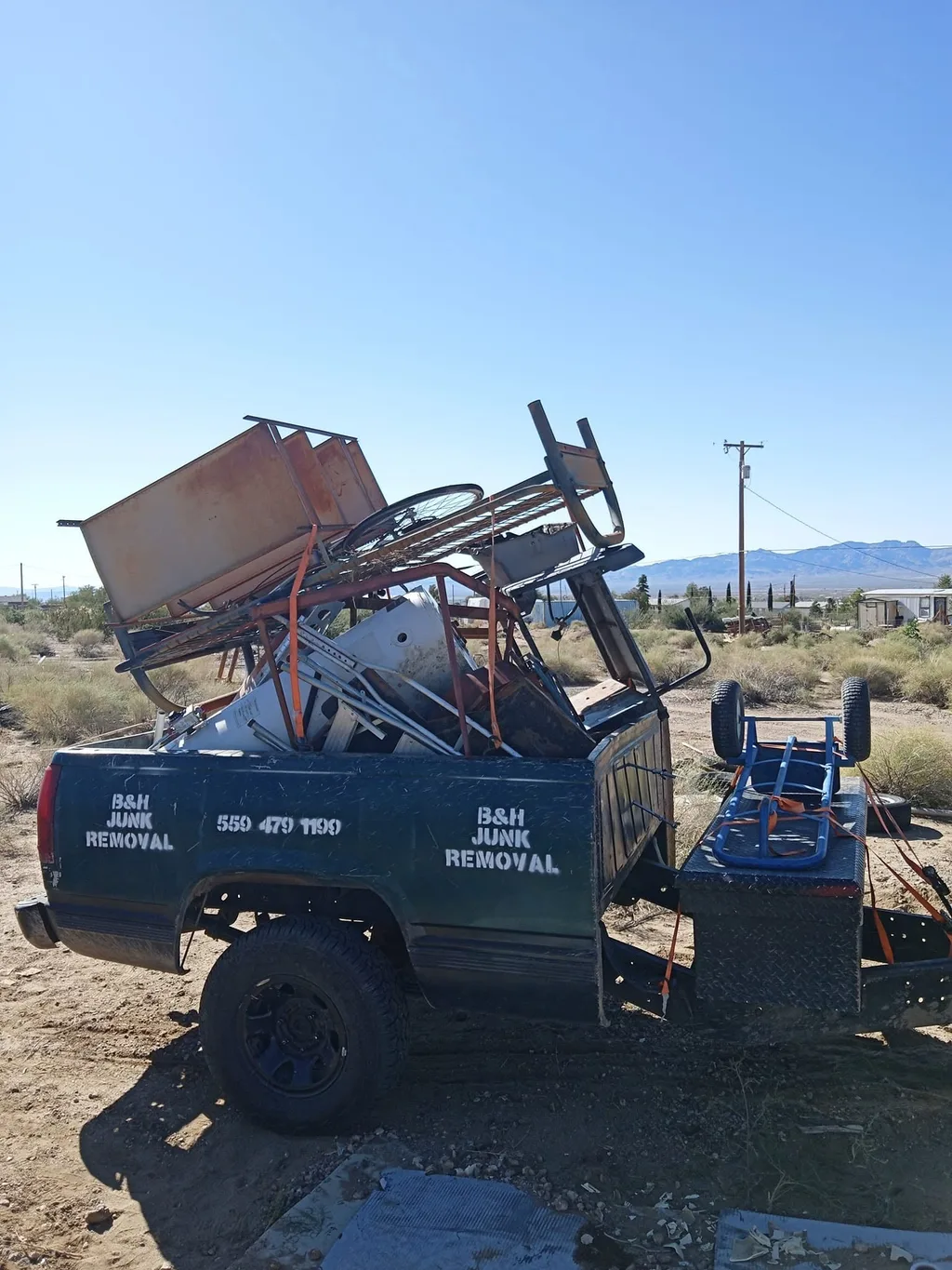 The B&H Junk Removal truck loaded with scrap metal, bed frames and an old bicycle