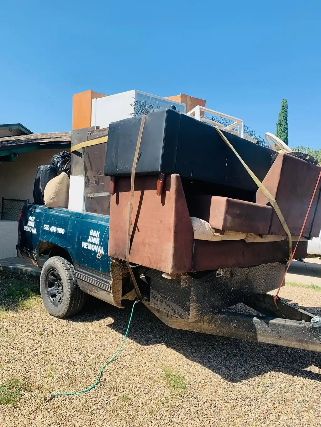 Sofas, cabinets and a mattress strapped onto the B&H Junk Removal truck
