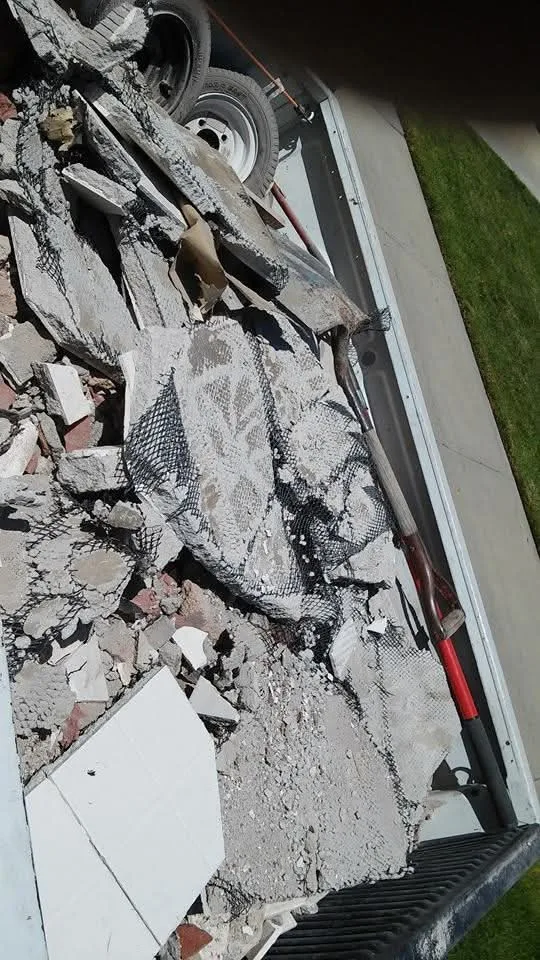 Broken concrete and stucco debris loaded level in a truck bed