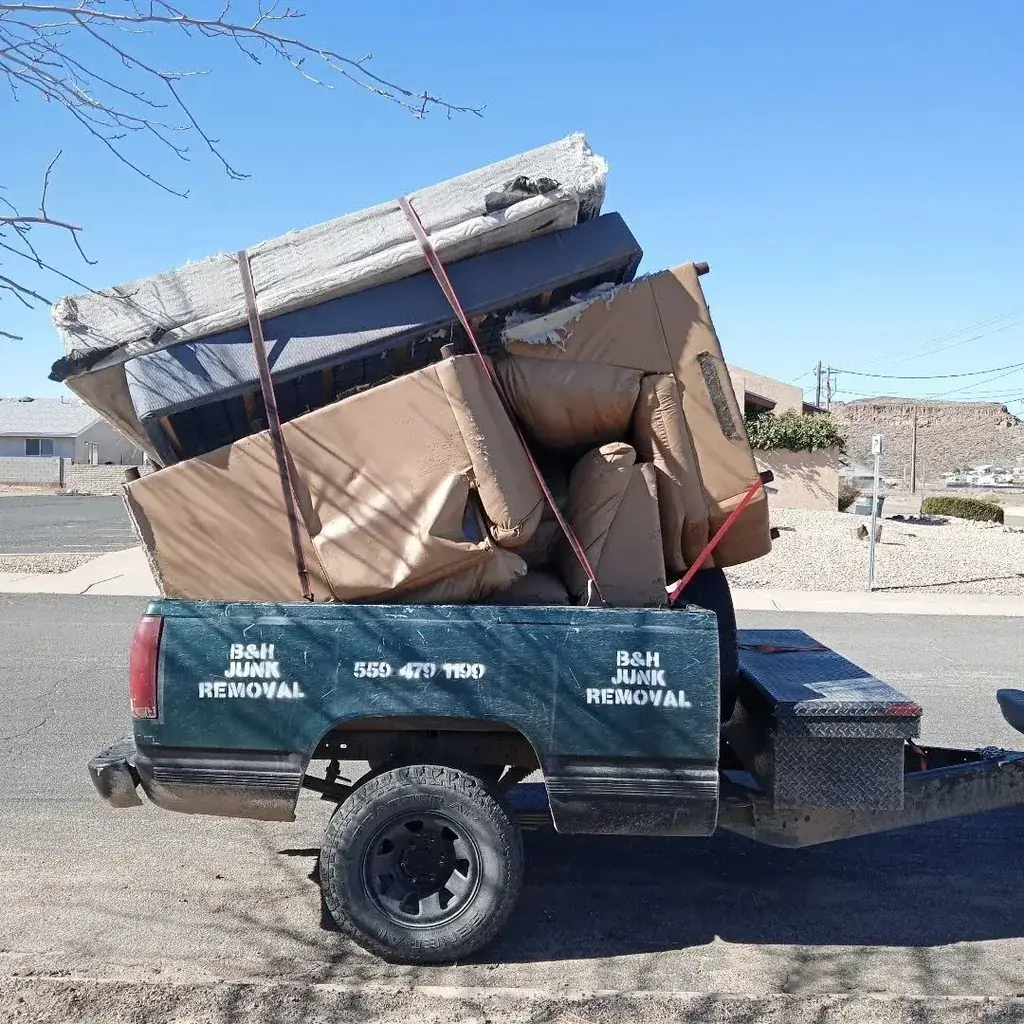 Cut branches, brush and scrap boards piled across a lawn before a yard cleanup