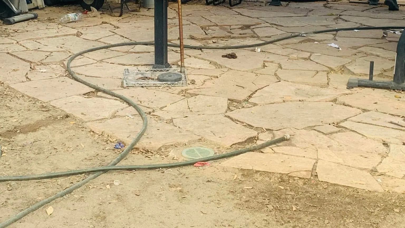 A man at work on a cluttered patio; exercise equipment; crates and bagged waste waiting to be carried out