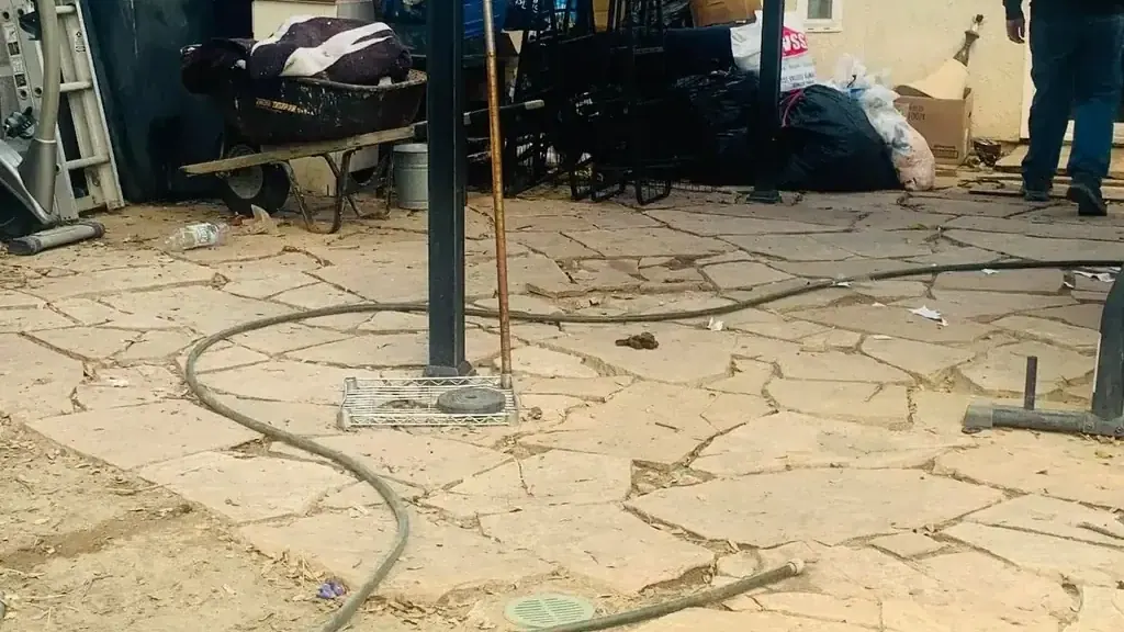 A patio cluttered with exercise equipment; a ladder and a wheelbarrow