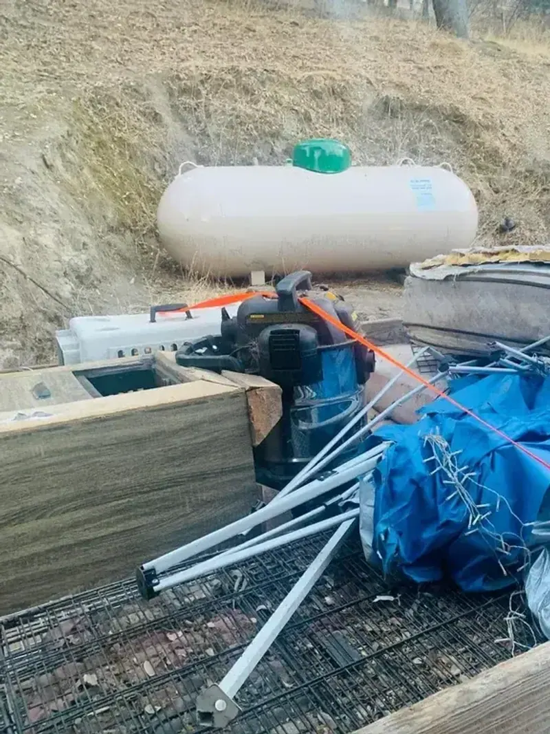 A trailer loaded with a mattress; a pool cover and yard items