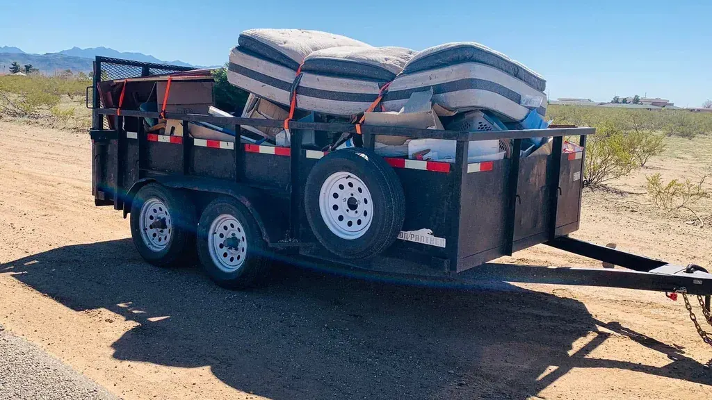A dump trailer loaded with mattresses and household debris