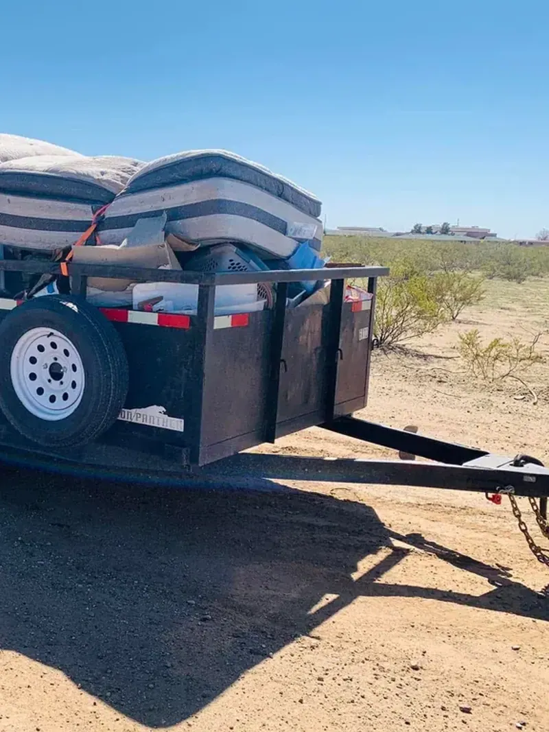 A dump trailer loaded with mattresses and household debris