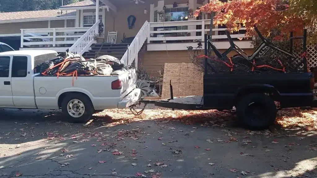 A truck and trailer loaded with patio furniture and yard debris