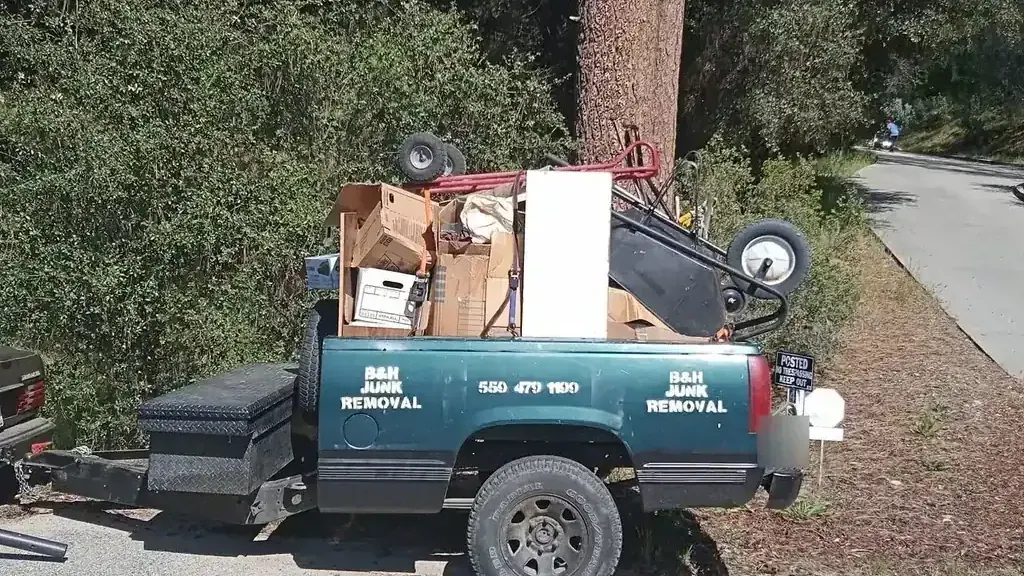 The B&H Junk Removal truck loaded with boxes; a lawn mower and a small fridge