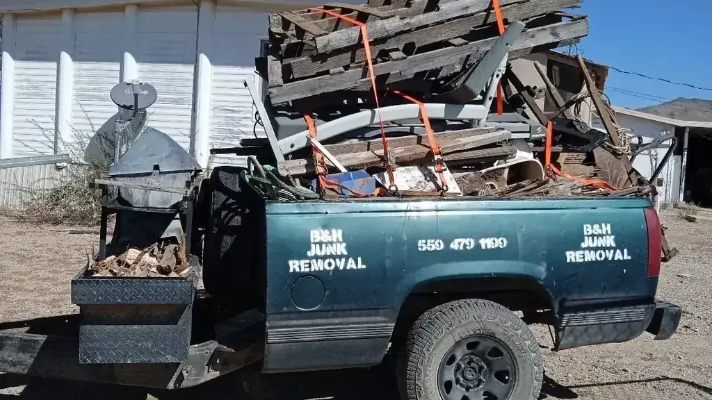 The B&H Junk Removal truck loaded with weathered fence boards and scrap lumber