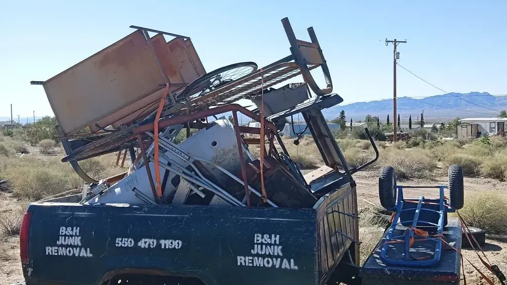 The B&H Junk Removal truck loaded with scrap metal; bed frames and an old bicycle