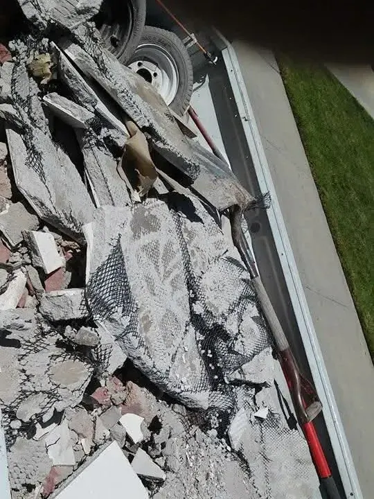 Broken concrete and stucco debris loaded level in a truck bed