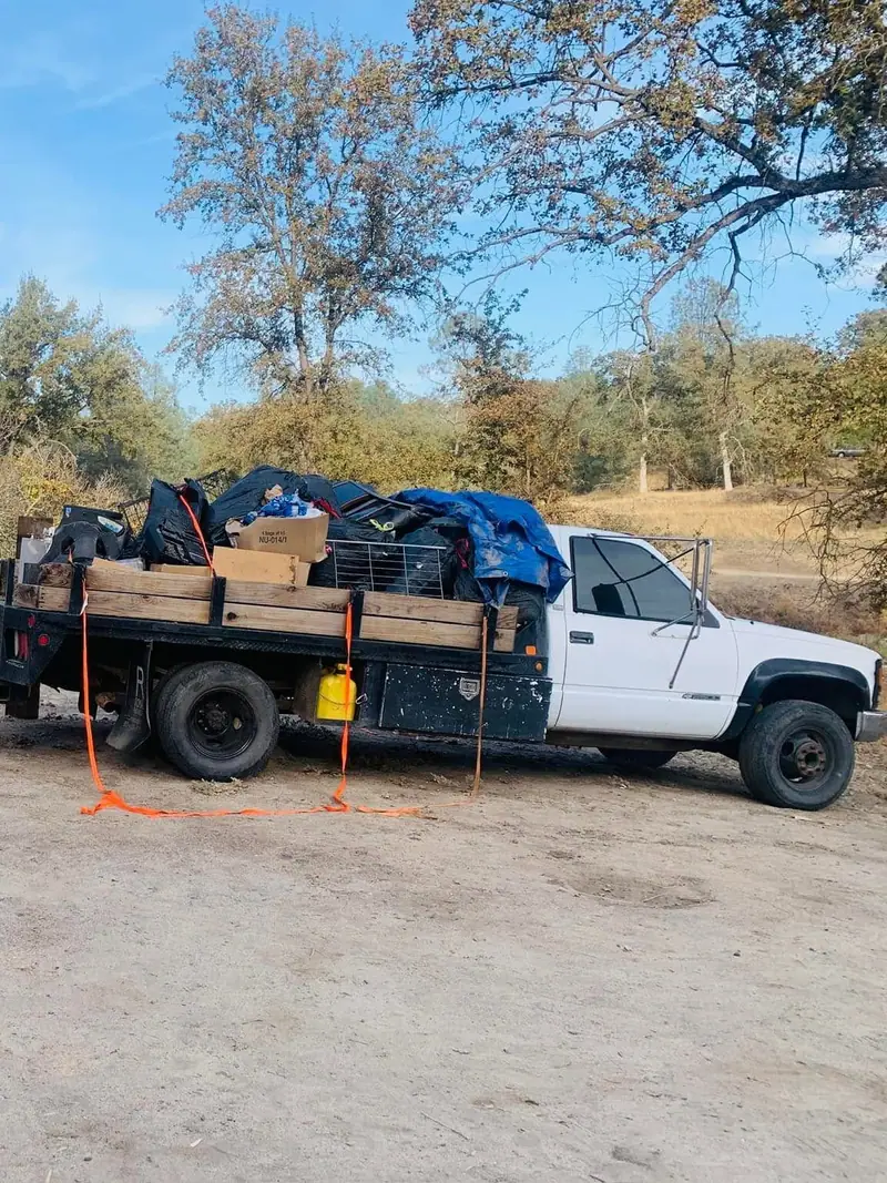 A flatbed and a towed trailer both loaded to the rails with bins; boxes and bagged waste