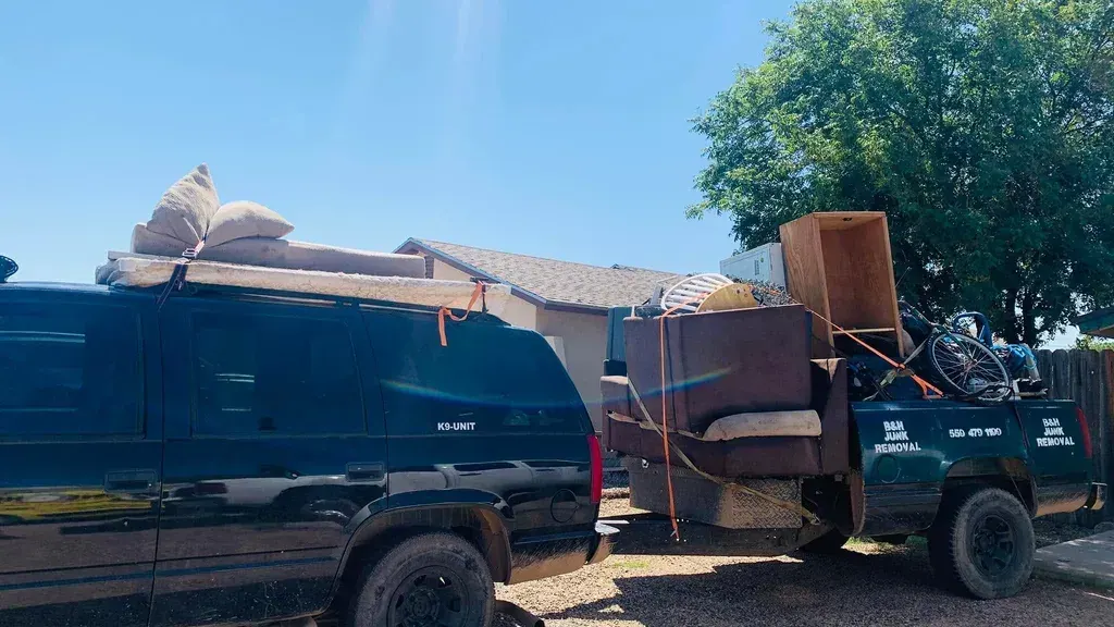 The B&H Junk Removal truck and trailer loaded with a sofa; cabinets and a bicycle