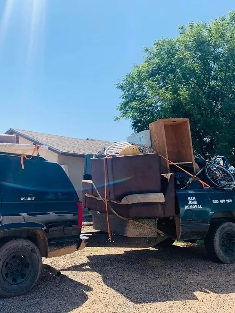The B&H Junk Removal truck and trailer loaded with a sofa; cabinets and a bicycle