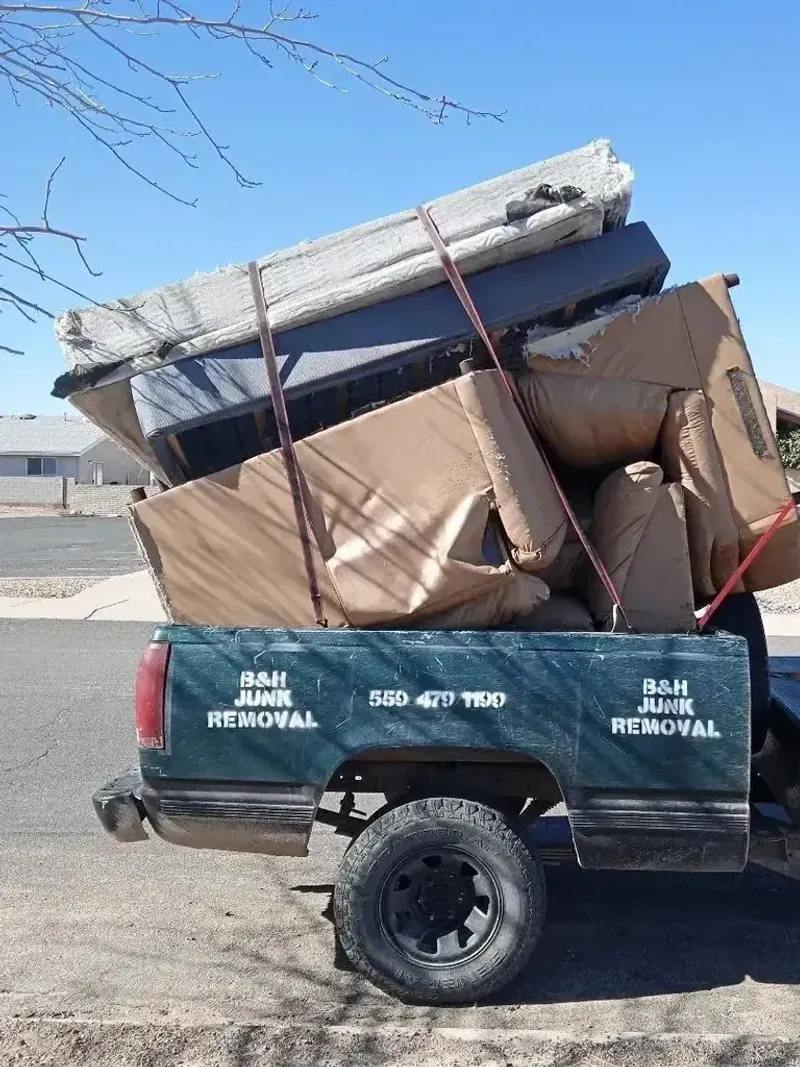 Cut branches; brush and scrap boards piled across a lawn before a yard cleanup